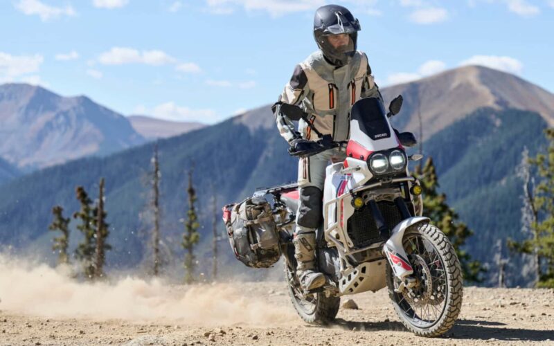motocicleta de tip adventure fotografiata pe teren accidentat cu peisaj montan in spate