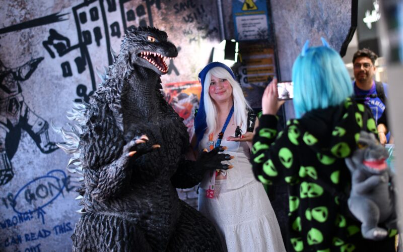 o fana costumata se pozeaza cu personajul Godzilla in cadrul conferintei comic 2025 con