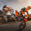 doua motociclete portocalii de la ktm fotografiate pe pista