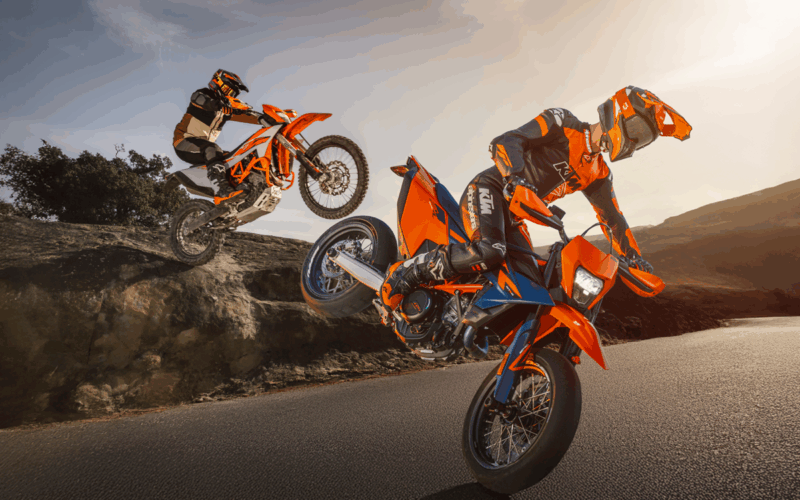 doua motociclete portocalii de la ktm fotografiate pe pista