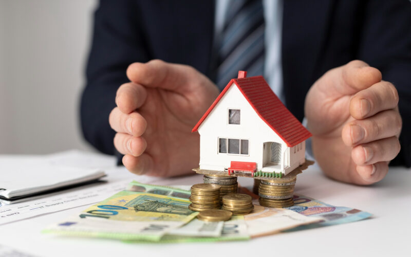 o imagine cu bani si o casa care ilustreaza o investitie in imobiliare