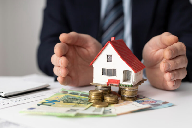 o imagine cu bani si o casa care ilustreaza o investitie in imobiliare