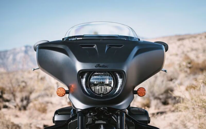 motocicleta cruiser neagra indian cu farul in prim plan si un munte in spate