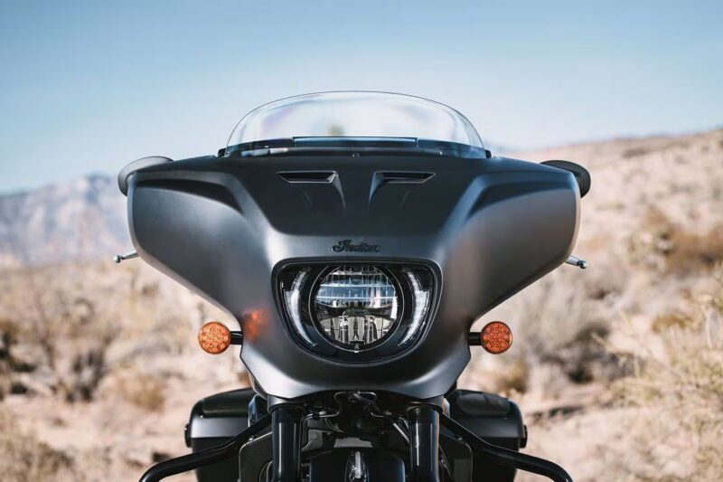 motocicleta cruiser neagra indian cu farul in prim plan si un munte in spate