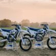 doua motociclete albe pe stativ la marginea unui camp