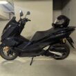 scuter honda de culoare albatra cu casca pusa pe sa fotografiat in subsol