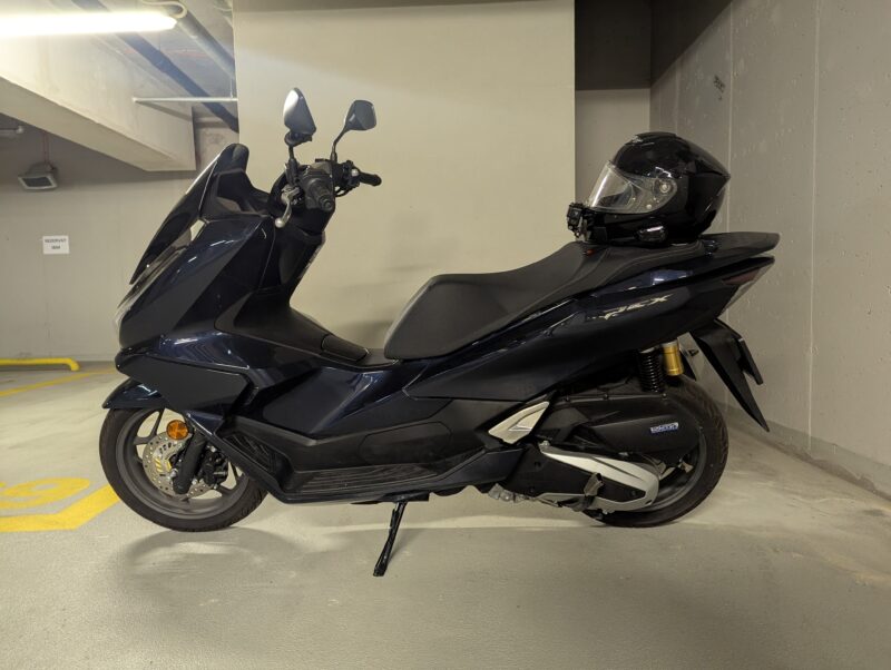 scuter honda de culoare albatra cu casca pusa pe sa fotografiat in subsol