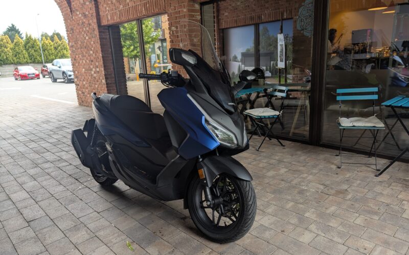 scuter albastru de la honda fotografiat in fata unei cafenele