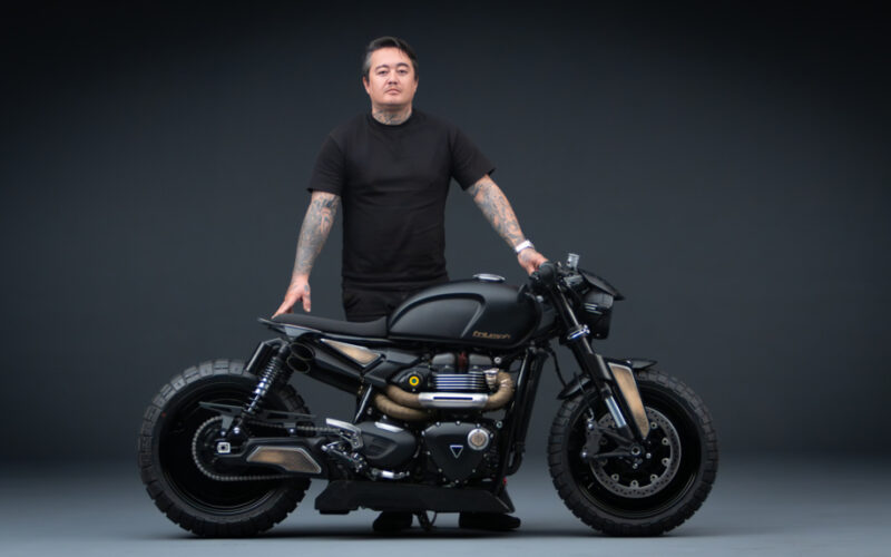 motocicleta custom made neagra alaturi de rider pe fundal negreu