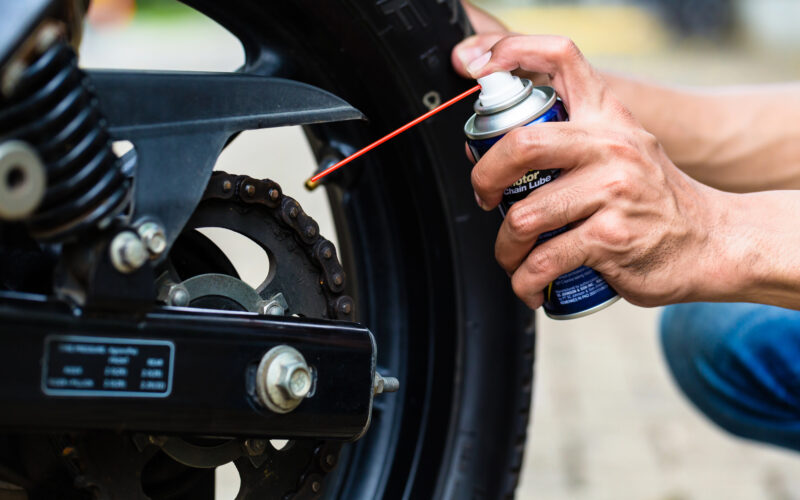 un posesor de motocicleta aplica ulei pe lant