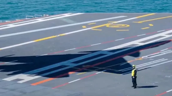 imagine in care se vede umbra unui avion pe pista de decoalre de pe un portavion