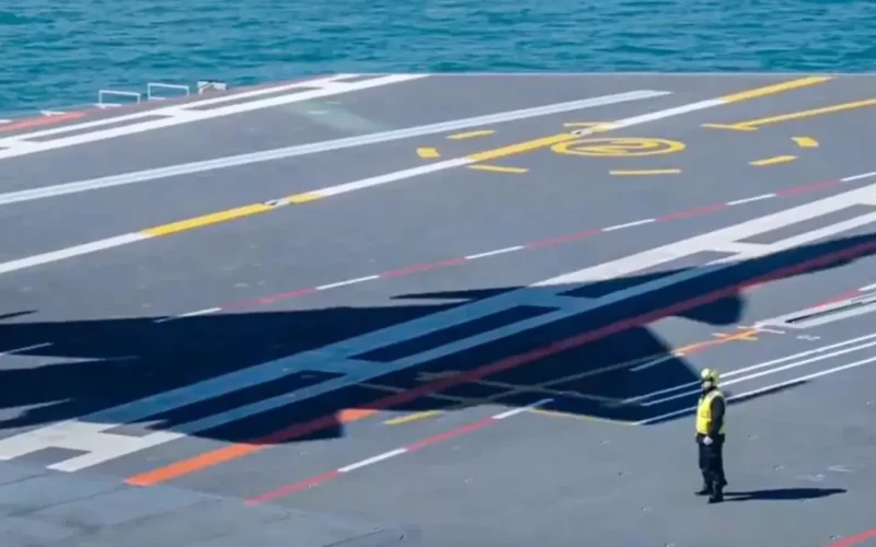 imagine in care se vede umbra unui avion pe pista de decoalre de pe un portavion