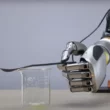 o mana robotica care tine o lingurita deasupra unui pahar
