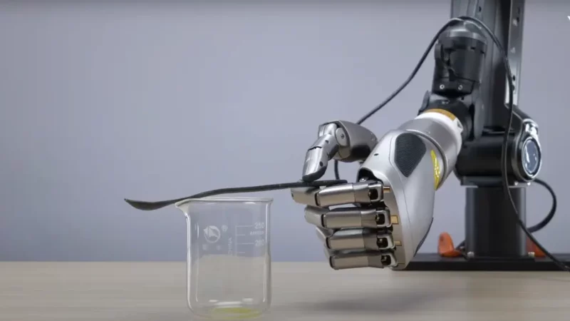 o mana robotica care tine o lingurita deasupra unui pahar