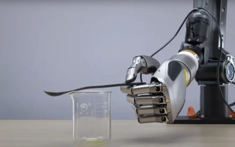 o mana robotica care tine o lingurita deasupra unui pahar