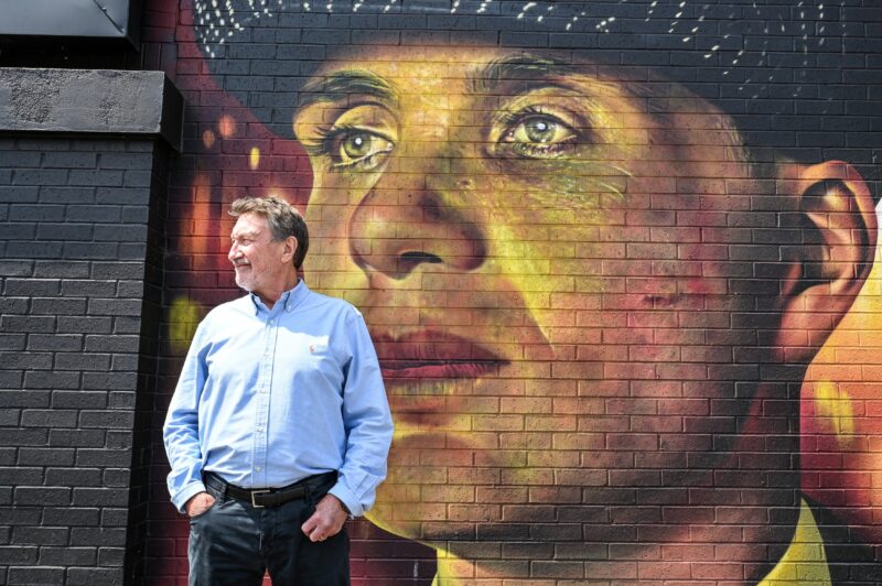 Steven Knight, creatorul peaky blinders, langa o imagine pictata pe perete care il arata pe thomas shelby