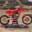 motocicleta enduro de culoare rosie fotografiata pe teren accidentat