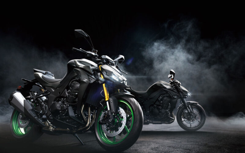 doua motociclete naked de culoare gri intr-un fundal negru cu fum