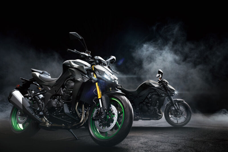 doua motociclete naked de culoare gri intr-un fundal negru cu fum