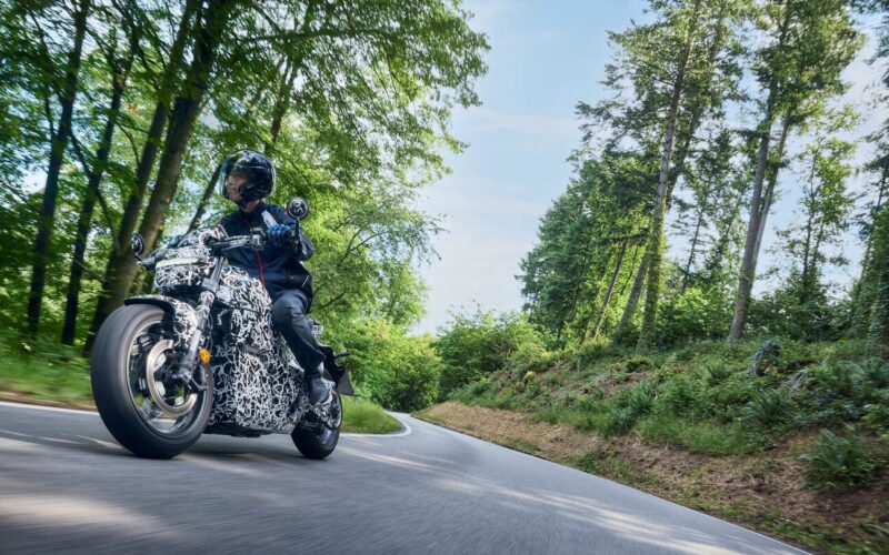 motocicleta honda electrica surprinsa pe un drum de munte intre copaci