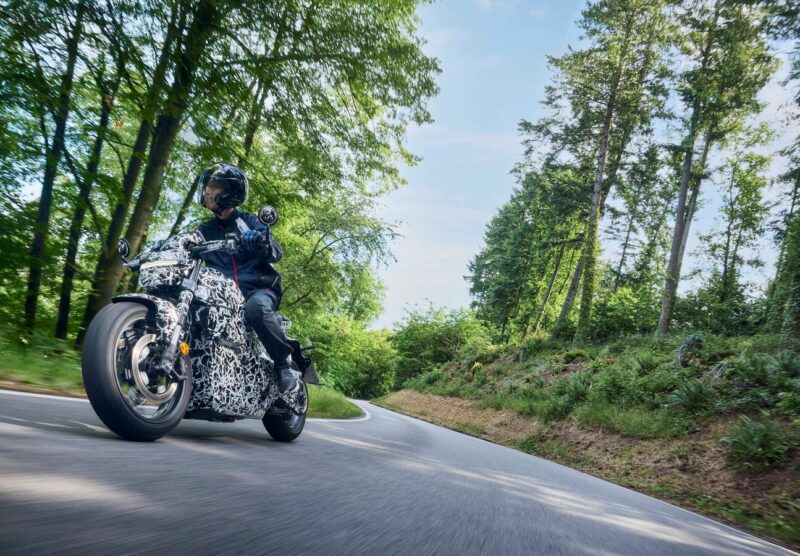 motocicleta honda electrica surprinsa pe un drum de munte intre copaci