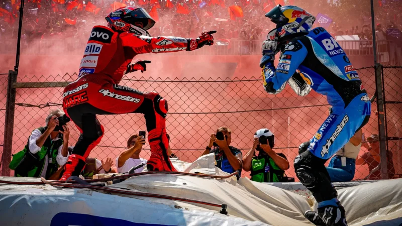 doi piloti motogp in fata multimii unul imbracat in rosu altul in albastru
