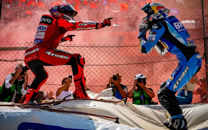 doi piloti motogp in fata multimii unul imbracat in rosu altul in albastru