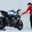 motociclist si motocicleta in fata unui perete alb