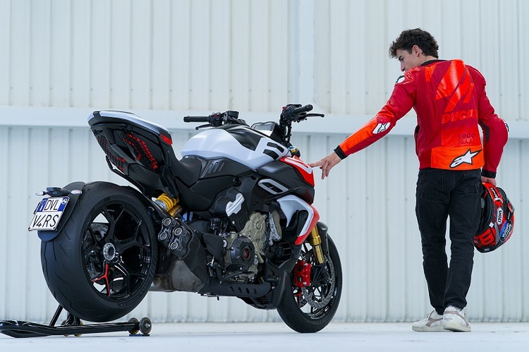 motociclist si motocicleta in fata unui perete alb