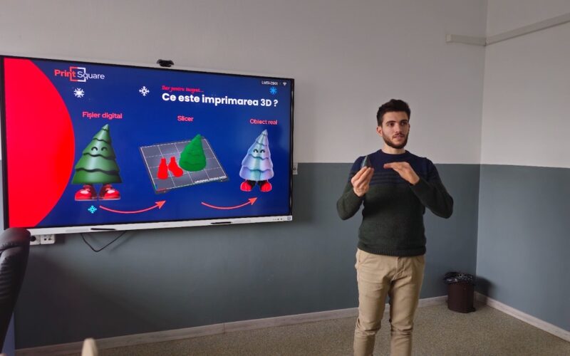 un om care vorbeste intr-o sala de clasa langa o tabla electronica