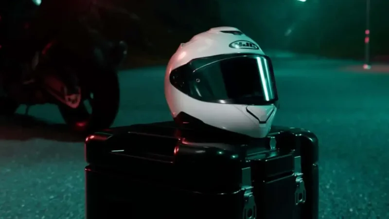 casca moto de culoare alba pusa peste un cufar
