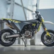 motocicleta super moto de culoare gri fotografiata cu o cladire de sticla in spate