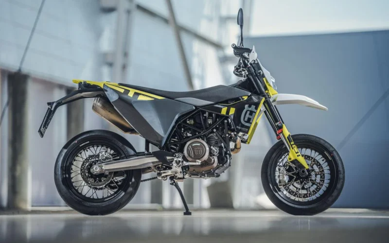 motocicleta super moto de culoare gri fotografiata cu o cladire de sticla in spate