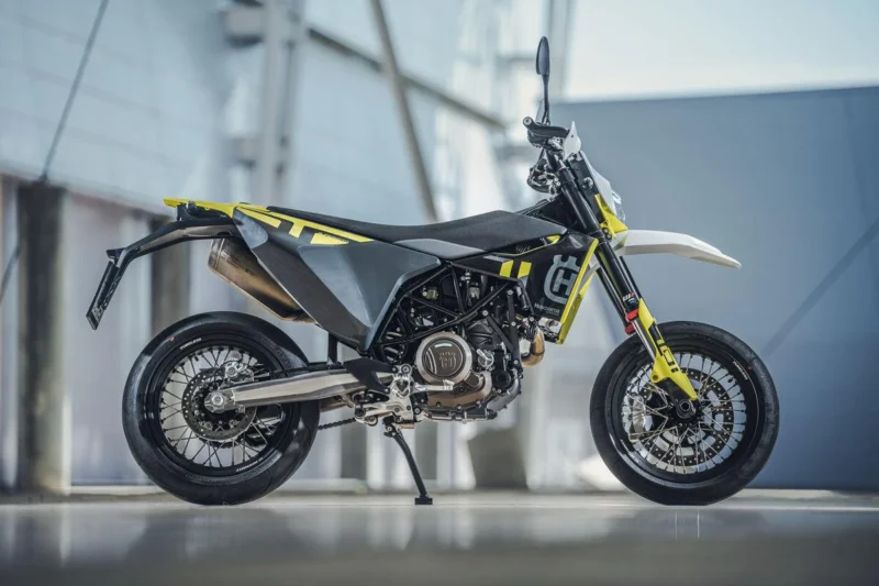 motocicleta super moto de culoare gri fotografiata cu o cladire de sticla in spate