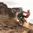 motociclist surpins in timp ce escaladeaza teren accidentat cu motocicleta pe o roata
