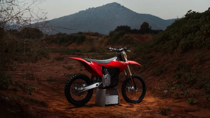 motocicleta electrica rosie pe pedestal cu un munte in fundal