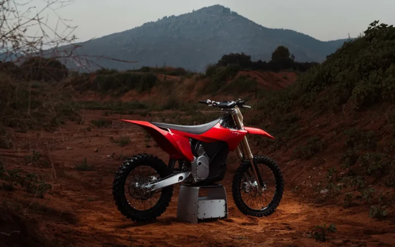 motocicleta electrica rosie pe pedestal cu un munte in fundal