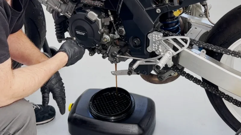 recipient negru ce colecteaza uleiul utilizat dintr-o motocicleta