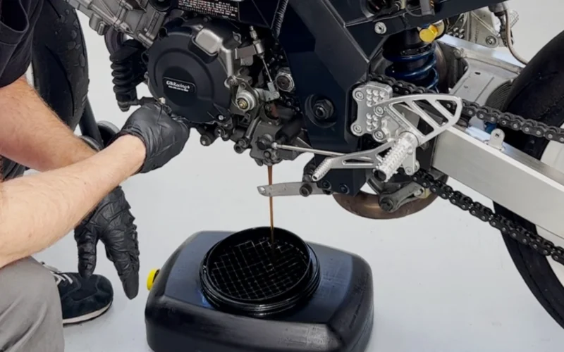 recipient negru ce colecteaza uleiul utilizat dintr-o motocicleta