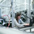 o femeie care lucreaza la un laptop intr-un mediu industrial