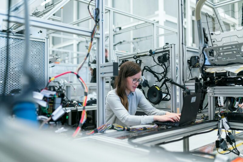 o femeie care lucreaza la un laptop intr-un mediu industrial