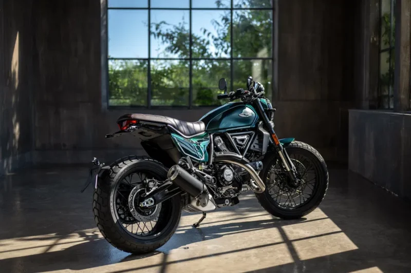 motocicleta scrambler de culoare verde fotografiata intr-o incapere langa o fereastra