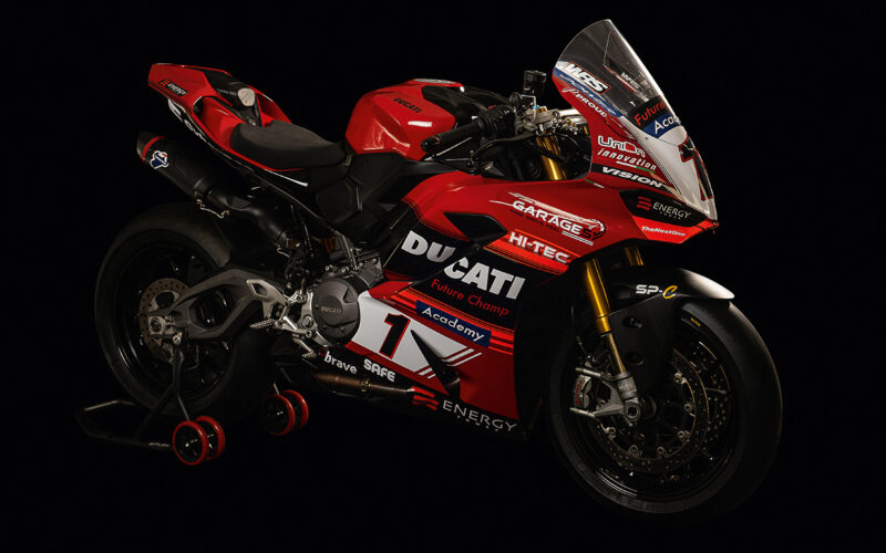 motoocicleta ducati rosie cu stikere pe fundal negru