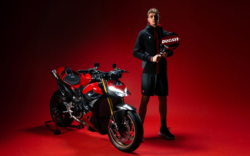o motocicleta rosie naked pe fundal ros cu un rider langa
