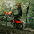 motocicleta enduro de culoare portocalie intr-o padure