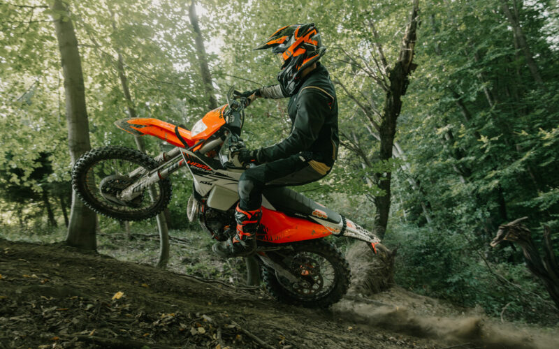 motocicleta enduro de culoare portocalie intr-o padure