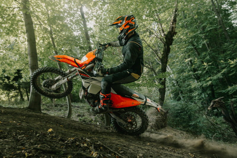 motocicleta enduro de culoare portocalie intr-o padure