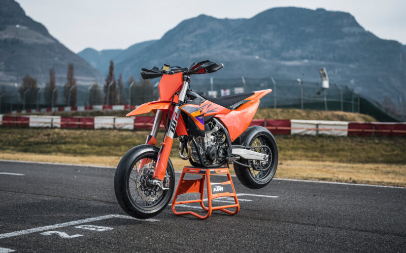 motocicleta portocalia pe pista de circuit cu un munte in fundal