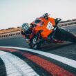 motocicleta portocalie pe circuit inclinata pe partea dreapta