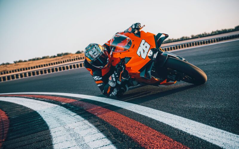 motocicleta portocalie pe circuit inclinata pe partea dreapta